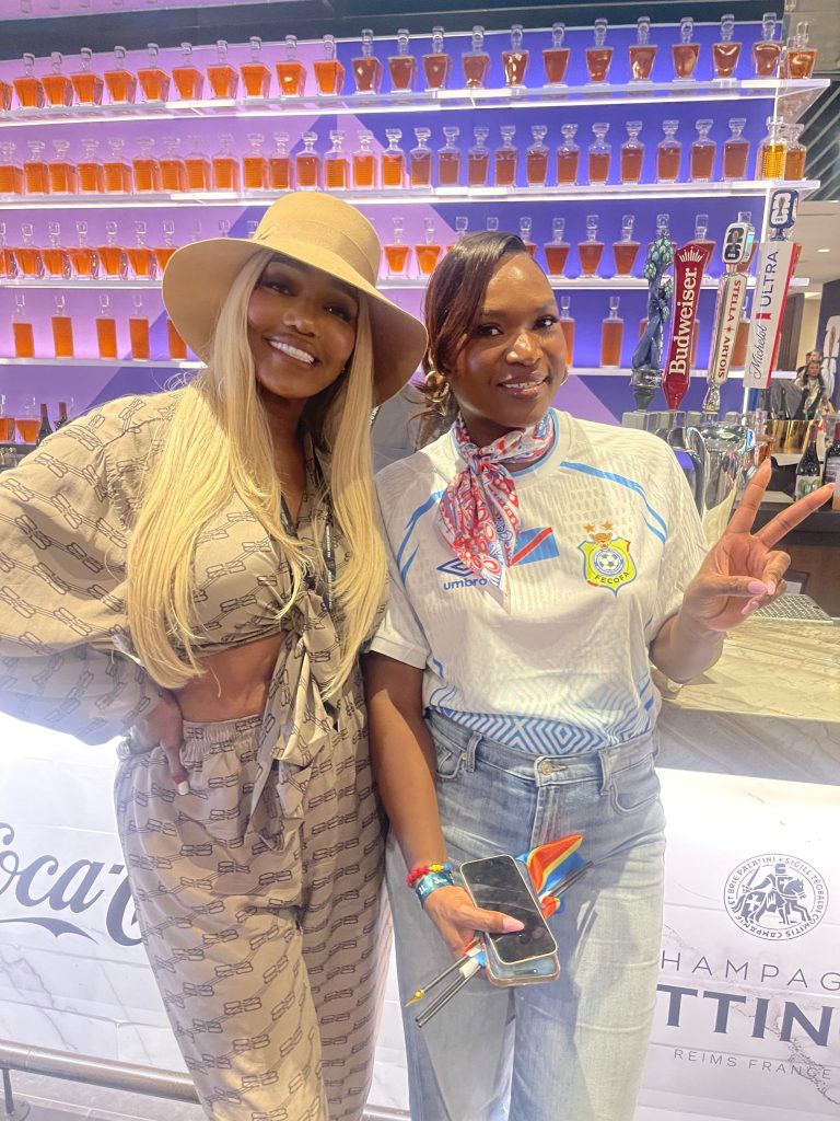 Two women in front of a colorful bottle display at a World Cup 2026 event